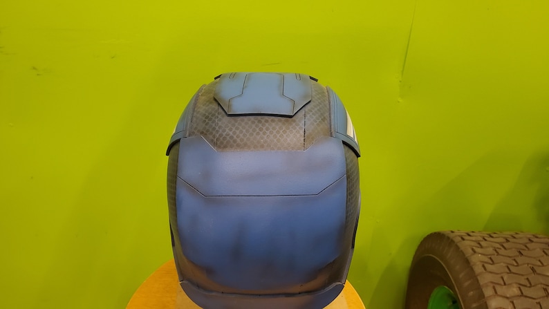 May include: A blue and black helmet with a textured surface. The helmet has a raised panel on the top and a white stripe on the side.