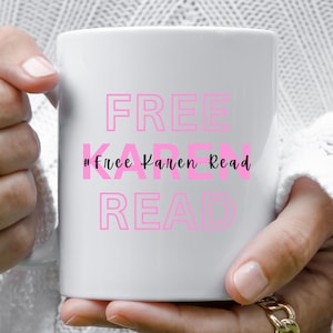Puede incluir: Taza de cerámica blanca con las palabras "FREE" y "READ" en letras rosas. La frase "#Free Karen Read" está en una fuente cursiva más pequeña. La taza está sostenida por una persona.