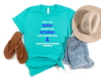 May include: Teal blue t-shirt with the text "I don't look sick? You don't look stupid! Looks can be deceiving" and a blue ribbon. The text "Chronic Fatigue Syndrome Awareness" is below the ribbon.