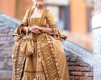 May include: A woman in a gold and brown patterned dress with a ruffled skirt and a large pink wig. She is standing on a set of stone steps.