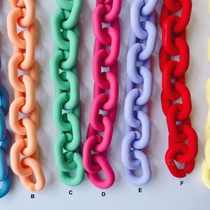 May include: A collection of colorful chain links in various shades, including blue, peach, green, pink, lavender, red, and yellow. The chains are arranged vertically, showcasing their vibrant hues and glossy finish. The image is well-lit, highlighting the smooth texture of the links.