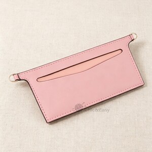 May include: A rectangular light pink leather card holder featuring a horizontal slot with a curved top edge, dark stitching along the perimeter, and two small metal rings attached to the upper corners. The text Chic&Easy is printed in the corner.