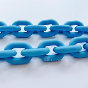 May include: Close-up of two rows of blue chain links with white inner links. The links are a solid, matte blue color. The image is set against a white background.