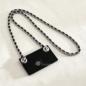 May include: A rectangular black tag with two silver-toned metal grommets at the top corners, attached to a long silver chain interwoven with a black ribbon. The tag features a small graphic of a ball of yarn with needles and the text Chic&Easy.