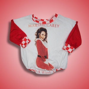 May include: White long-sleeve shirt with red and white checkered trim. The shirt features a printed image of Mariah Carey in a red Santa suit with the text "Mariah Carey" and "All I Want For Christmas Is You".