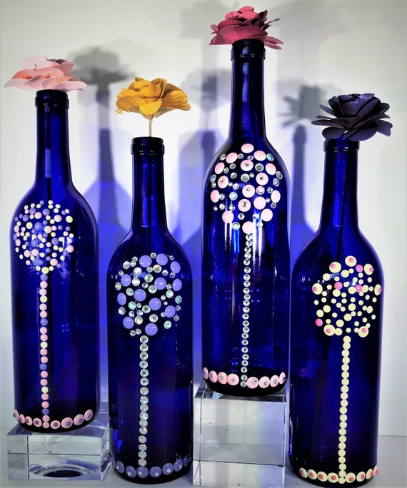 Decorative Bottles Made With Colorful Enamel Dots That Sparkle Against Blue Bottle. A Perfect Gift or Unique Home Decor. 25.00 Each. - Etsy These decorative bottles are handcrafted with colorful enamel dots that sparkle against a blue background, creating a stunning visual display. They make a perfect gift for a loved one or a unique addition to any home decor collection, available for purchase on Etsy for 25.00 each.