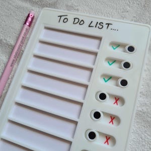 May include: White to-do list board with eight blank spaces for writing tasks. Each space has a circle with a tick or a cross to indicate completion status. The board has the text "To Do List..." written at the top.