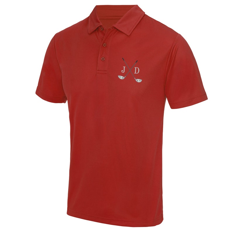 May include: Red short-sleeved polo shirt with a white embroidered design of two crossed golf clubs and the initials "J D".