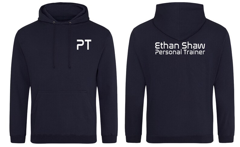 May include: A navy blue hooded sweatshirt with white text on the front and back. The front says "PT" and the back says "Ethan Shaw Personal Trainer".