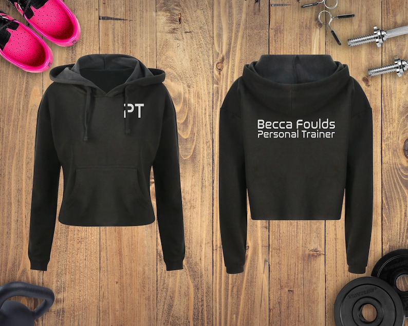 May include: Black cropped hoodie with a white text design. The text on the front says "IPT" and the text on the back says "Becca Foulds Personal Trainer".