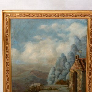 May include: A framed oil painting depicting a landscape with a stone building in the foreground. The building has a rounded archway and a stone roof. The background features a mountainous landscape with a cloudy sky.