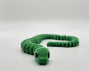 May include: A green plastic toy snake with black eyes. The snake is curled up in a coil.