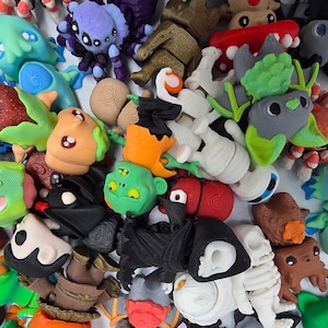 May include: A collection of small, multi-colored 3D printed figurines featuring various creatures, including spiders, skeletons, bats, and pumpkin-themed characters in shades of orange, green, purple, black, white, and brown.