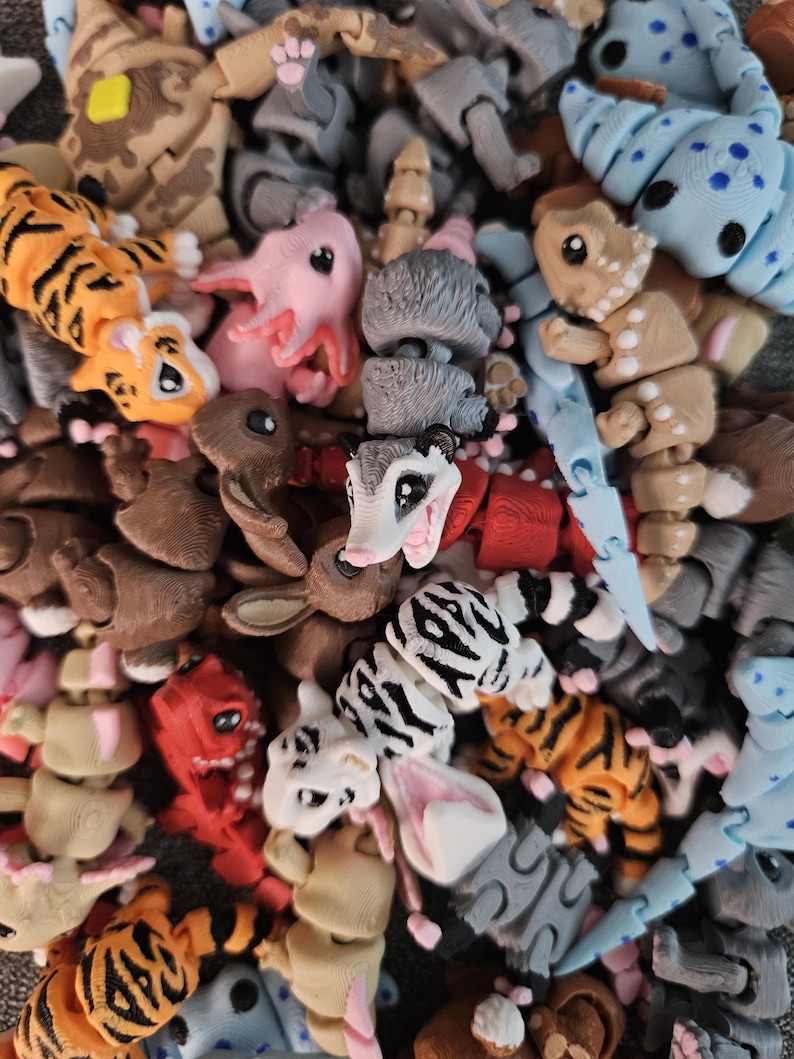 Puede incluir: Una colecci&oacute;n de juguetes de animales articulados y coloridos. El surtido incluye tigres con rayas naranjas y negras, ajolotes rosas, conejos y otras criaturas en varios colores y patrones. Los juguetes parecen ser de pl&aacute;stico.