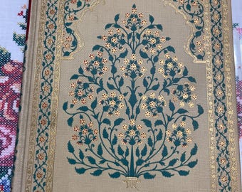 Könnte beinhalten: Ein beiges Journal mit einem grünen und goldenen floralen Design auf dem Umschlag. Das Design zeigt einen stilisierten Baum mit filigranen Ästen und Blättern. Der Rand des Umschlags ist mit einem sich wiederholenden Muster aus Grün und Gold verziert.