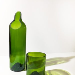 Peut inclure: Deux bouteilles en verre vert, l'une haute et étroite avec une large ouverture, l'autre plus courte et plus large, toutes deux avec un fond arrondi.