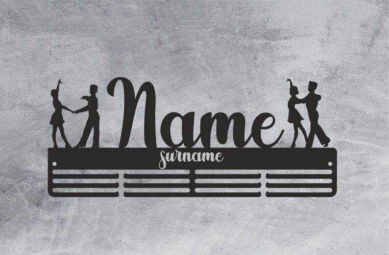May include: Black metal wall-mounted medal display with a silhouette of two dancers. The display has a personalized name and surname.
