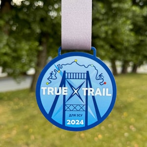May include: A blue and white medal with the text "TRUE X TRAIL" and "ДЛЯ ЗСУ 2024" in a white circle. The medal features a stylized image of a bridge with a trail running over it.