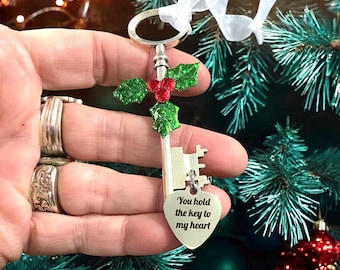May include: Silver key Christmas ornament with a holly sprig and a heart-shaped tag that reads "You hold the key to my heart".