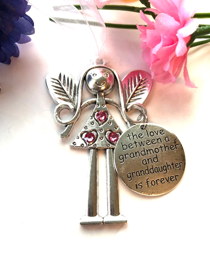 May include: Silver angel figurine with pink glitter hearts and a charm that reads "the love between a grandmother and granddaughter is forever".