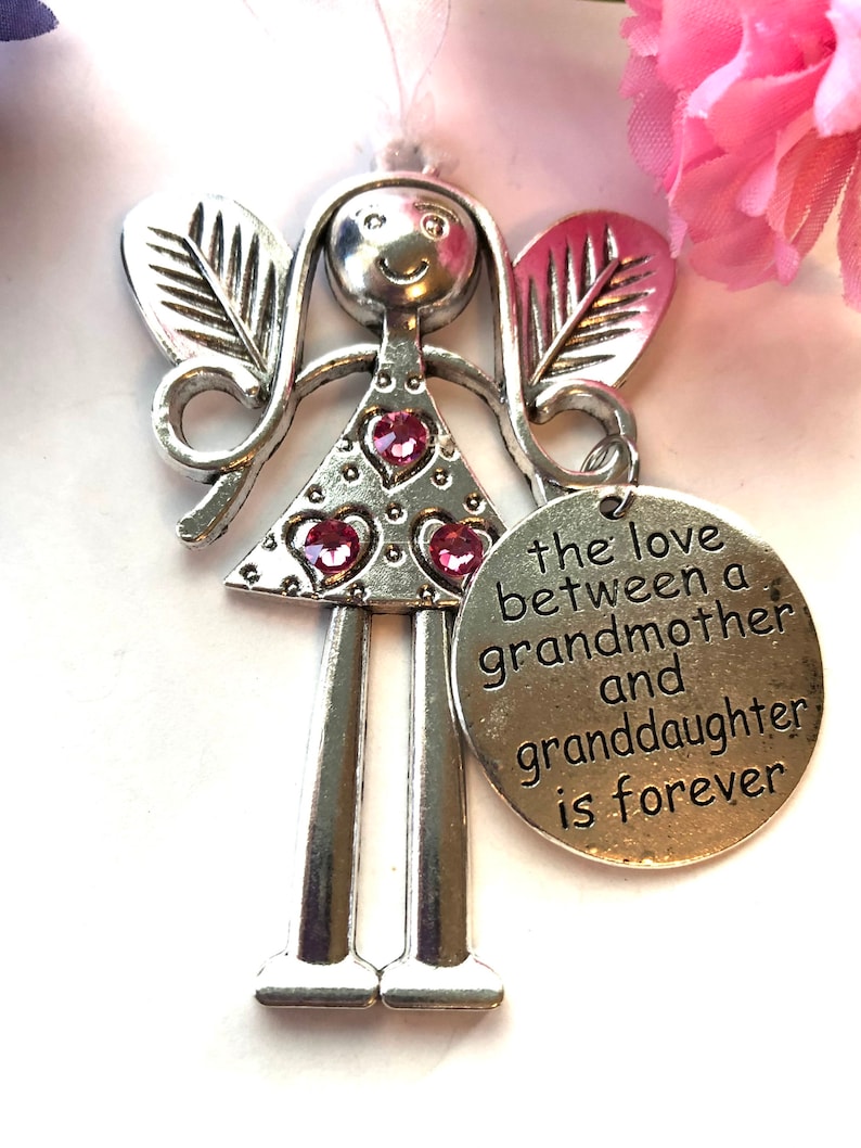 May include: Silver angel figurine with pink glitter and a heart-shaped charm that reads "the love between a grandmother and granddaughter is forever".