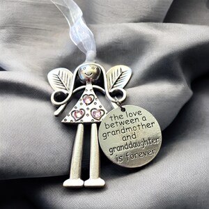 May include: Silver angel ornament with pink rhinestones and a round charm that reads "The love between a grandmother and granddaughter is forever".