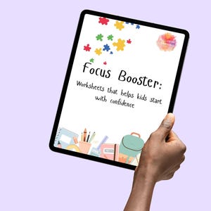 Op de afbeelding: Een tablet toont de tekst "HELPS KIDS START TASKS & STAY FOCUSED" en "Focus Booster: Worksheets that helps kids start with confidence." Kleurrijke puzzelstukjes en schoolspullen zijn op het scherm afgebeeld. De tablet wordt door een hand vastgehouden.