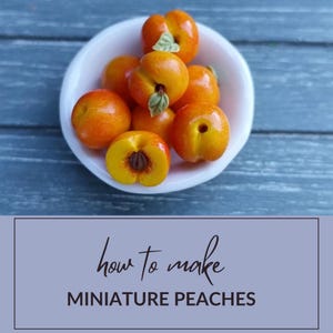 Puede incluir: Un bol blanco lleno de melocotones en miniatura. Los melocotones son de color naranja brillante y tienen una textura ligeramente peluda. El bol está sobre una superficie de madera azul. Cómo hacer melocotones en miniatura.
