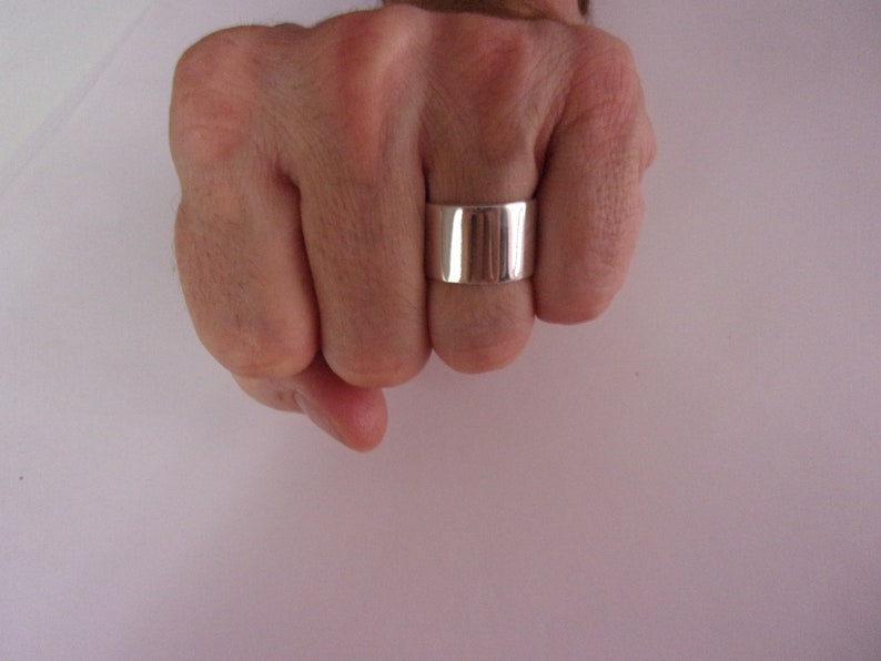 Peut inclure: Une bague en argent avec une bande large, plate et polie.