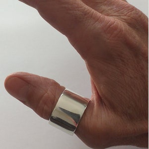 Peut inclure: Une bague de pouce en argent avec une bande large et plate.