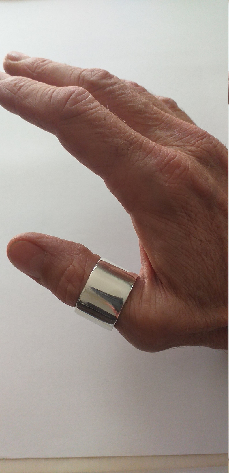 Peut inclure: Une bague de pouce en argent avec une bande large et plate.