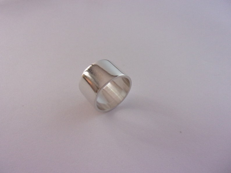 Peut inclure: Une bague en argent avec une bande large et plate.