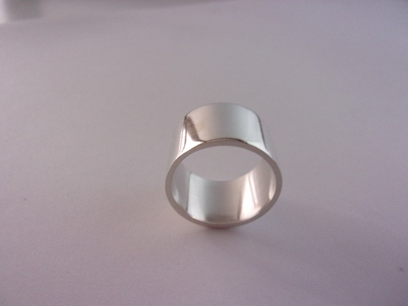 Peut inclure: Une bague en argent avec une bande large et une finition lisse et polie.