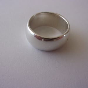 May include: A silver wedding band with a smooth, rounded surface.