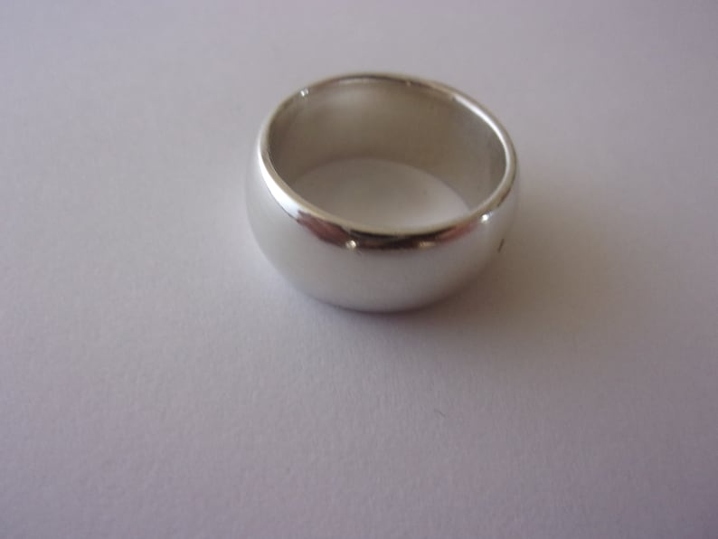 May include: A silver wedding band with a smooth, rounded surface.