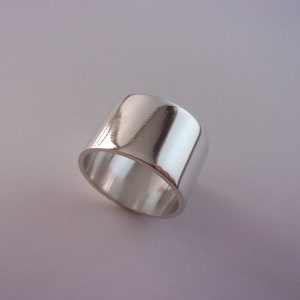 Peut inclure: Une bague large en argent avec une finition lisse et polie.
