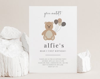 May include: A white invitation card with a brown teddy bear holding balloons. The text on the card reads "you're invited to alfie's BEAR-Y FIRST BIRTHDAY!" and includes details for the birthday party.