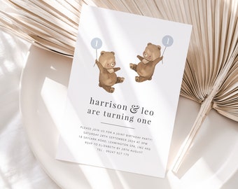 Könnte beinhalten: Eine weiße Einladungskarte mit einer Illustration eines braunen Bären, der einen blauen Ballon mit der Nummer 1 hält. Der Text auf der Karte lautet "harrison & leo werden ein Jahr alt". Die Einladung beschreibt eine gemeinsame Geburtstagsfeier für die beiden Jungen am 28. September 2024 um 15 Uhr. Die Adresse und die RSVP-Informationen sind ebenfalls enthalten.