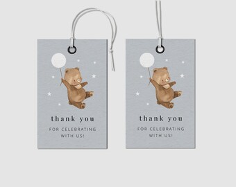 May include: Two grey gift tags featuring a watercolour illustration of a brown bear holding a white balloon. The text "thank you for celebrating with us!" is printed in black. Each tag has a white string.