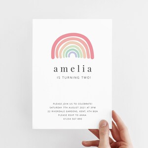 May include: A rainbow-colored birthday invitation with the name Amelia and the text "Is turning two!"  The invitation also includes the date, time, and location of the party.