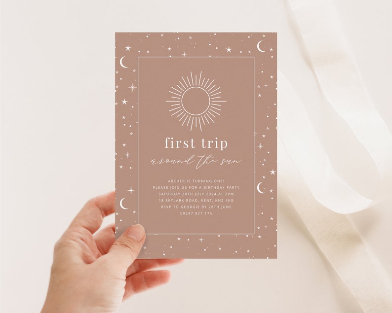 May include: A light brown invitation card with a white sun and moon design. The text reads "first trip around the sun" and includes details for a birthday party.