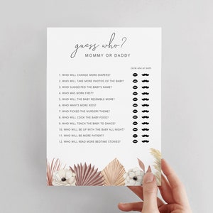 May include: A printable baby shower game with a white background and brown floral illustrations. The game asks guests to guess who will do certain things, like change more diapers or take more photos of the baby, between the mommy and daddy.  The game includes a list of 12 questions with a space to circle either mommy, daddy, or both.