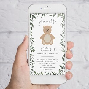 Puede incluir: Una invitaci&oacute;n digital para una fiesta de primer cumplea&ntilde;os con un borde de hojas verdes y un oso de peluche marr&oacute;n de dibujos animados. El texto dice "you're invited to alfie's BEAR-Y FIRST BIRTHDAY!" con detalles para la fiesta, incluyendo la fecha, la hora, la direcci&oacute;n y la informaci&oacute;n de RSVP.
