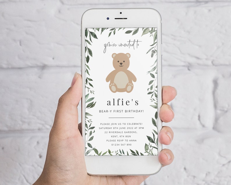 Puede incluir: Una invitaci&oacute;n digital para una fiesta de primer cumplea&ntilde;os con un borde de hojas verdes y un oso de peluche marr&oacute;n de dibujos animados. El texto dice "you're invited to alfie's BEAR-Y FIRST BIRTHDAY!" con detalles para la fiesta, incluyendo la fecha, la hora, la direcci&oacute;n y la informaci&oacute;n de RSVP.