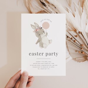 K&ouml;nnte beinhalten: Eine wei&szlig;e Einladungskarte mit einer Aquarell-Illustration eines Hasen, der einen rosa Ballon h&auml;lt. Der Text auf der Karte lautet "Join us for an easter party" und enth&auml;lt Details zur Veranstaltung, einschlie&szlig;lich Datum, Uhrzeit, Ort und RSVP-Informationen.