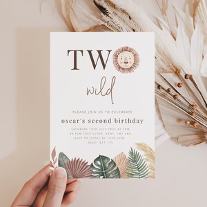 May include: A white invitation card with brown text that reads "TWO wild" and a cartoon lion face. The text below reads "Please join us to celebrate Oscar's second birthday" with details about the date, time, location, and RSVP information.