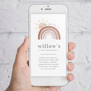 May include: A smartphone displaying a digital invitation for a first birthday party. The invitation features a rainbow with a sun and the text "YOU ARE INVITED TO willow's FIRST BIRTHDAY!"  The invitation also includes the date, time, location, and RSVP information.
