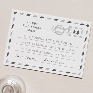 May include: A white card with a black and gray border. The card has a message that says "Happy Christmas Mum! This coupon entitles you to a spa treatment at the Willow followed by lunch at the Ivy. Love from: Hannah xo"