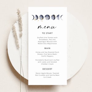 May include: A minimalist wedding menu card with a celestial theme. The card features a watercolor illustration of five moons with gold stars. The menu includes a starter, main course, and dessert.