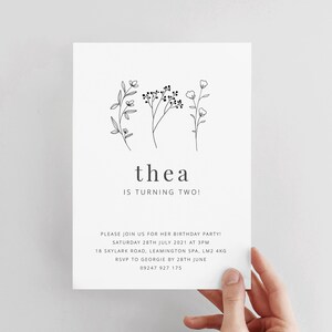 May include: A black and white birthday invitation for a child named Thea turning two. The invitation features a simple floral design and the text "thea is turning two!"  Please join us for her birthday party! Saturday 28th July 2021 at 3pm 18 Skylark Road, Leamington Spa, LM2 4KG RSVP to Georgie by 28th June 09247 927 175